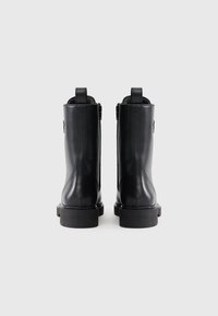 Μαύρες δερμάτινες μπότες αστραγάλου με λείο υφή, στρογγυλή μύτη, χοντρή σόλα και κατακόρυφες ραφές στη πλάτη και στα πλάγια.