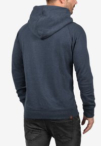 Felpa blu navy con tasca a marsupio, polsini e bordo a costine. Tessuto liscio e cappuccio regolabile con cordino. Vista posteriore mostrata.