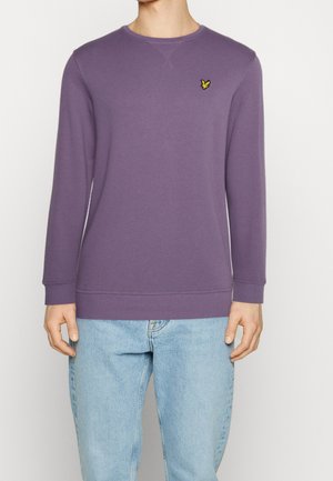 Lila Sweatshirt aus weichem Stoff, mit langen Ärmeln und Rundhalsausschnitt. Ein kleines gelbes Vogel-Logo ist auf der linken Brust gestickt.