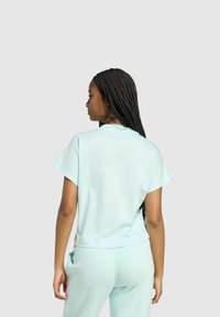 Top de manga corta de color azul claro hecho de una tela suave, con un corte relajado y un escote redondo, combinado con pantalones a juego en azul claro.