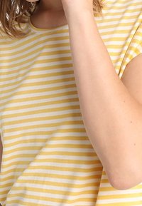 Żółto-biały pasiasty krótki rękaw bluzka z okrągłym dekoltem. Miękka bawełniana tkanina, luźny krój, widoczne szwy wzdłuż dołu.