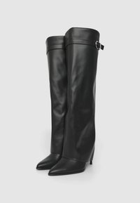 Stivali alti in pelle nera sopra il ginocchio con punta affusolata, dotati di un alto tacco a stiletto e di una fascia con una fibbia metallica nella parte superiore.