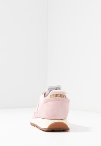 Baskets Saucony en daim rose vues de l'arrière sur une surface blanche avec un fond blanc bordé.