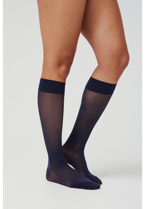 Marineblaue kniehohe Socken, durchsichtiger Stoff, glatte Textur, mit einem festen Bündchen oben. Fuß- und Beinabdeckung sichtbar.