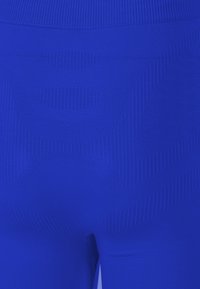 Leggings bleus texturés avec un design ajusté et des motifs côtelés variés, mettant en avant une coupe près du corps et un tissu lisse.