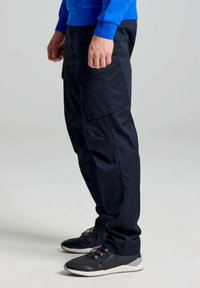 Pantaloni cargo blu navy con una vestibilità affusolata, dotati di tasche laterali, tessuto testurizzato e superficie liscia. Indossati con scarpe sportive nere.