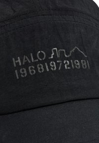 Czarna czapka z wypukłym napisem "HALO 196819721981" oraz prostym wzorem panoramy miasta. Materiał ma gładką, matową teksturę.
