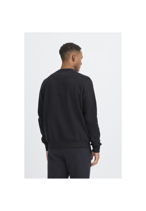 Sweat-shirt noir avec un col rond, des manches longues, des poignets et un ourlet côtelés. Tissu uni avec une texture lisse. Vue arrière présentée.