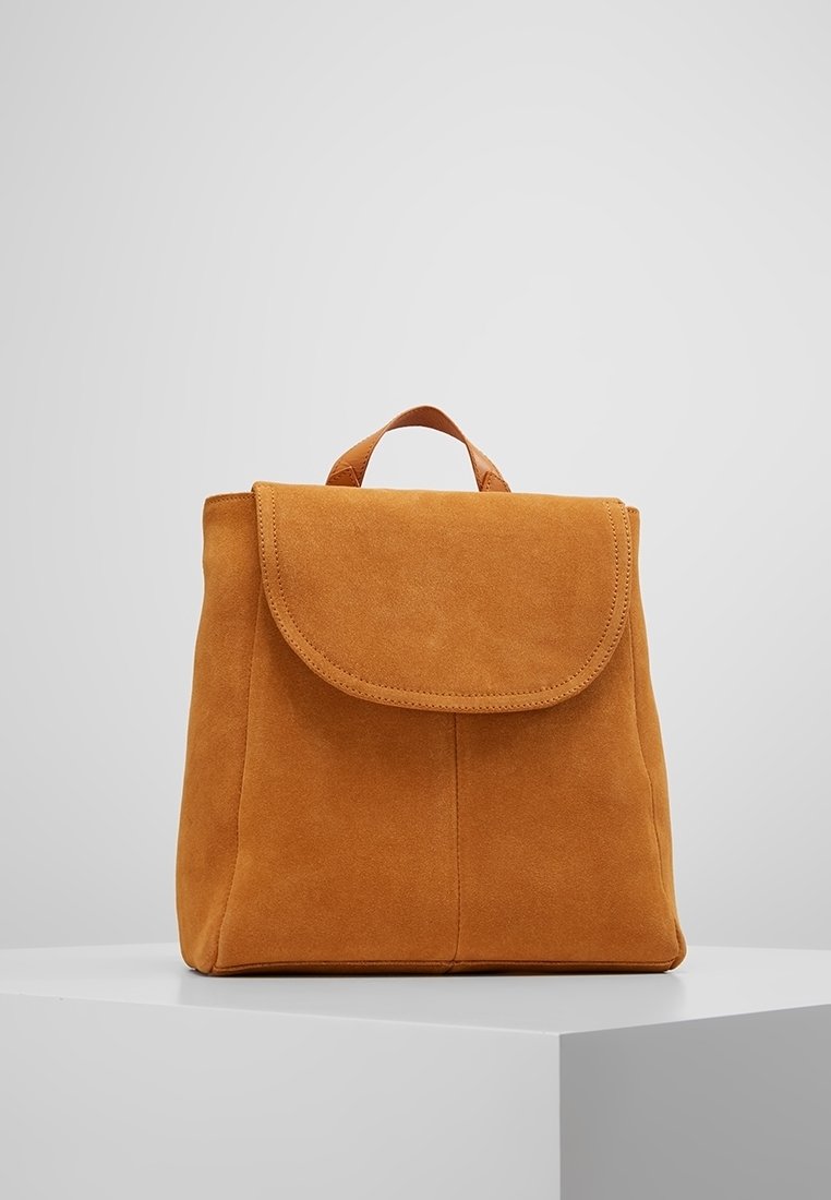 Mochila de ante en un cálido tono marrón-naranja, con cierre de solapa redondeada, asa superior y mínimo detalle de costuras para un diseño limpio.