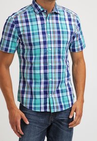 Kortärmad, knappad skjorta i blått och blågrönt rutmönster med vita och röda detaljer; har framficka och krage.