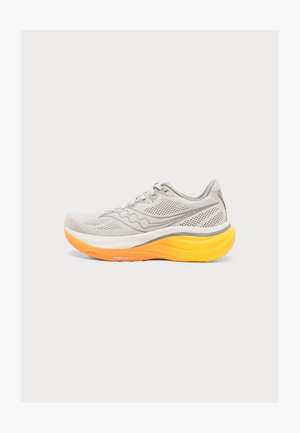 Ανοιχτό γκρι αθλητικό παπούτσι με πλέγμα στην πάνω επιφάνεια και παχύ, κίτρινο-πορτοκαλί μαξιλαρωμένο πέλμα, που φαίνεται από το πλάι σε λευκό φόντο.