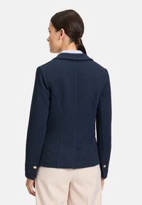 Granatowa marynarka wykonana z teksturowanej tkaniny, z klapami, dopasowanym krojem i złotymi guzikami na mankietach.