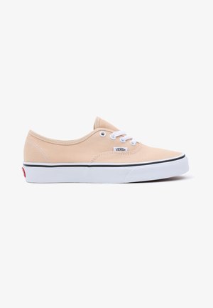 Beige Canvas-Sneaker mit weißen Schnürsenkeln, Gummisohle, schwarzem Rand und Logo-Tag an der Seite; Low-Top-Design und glatte Textur.