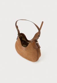 Sac à bandoulière en daim marron avec une sangle en cuir, un design incurvé et une poche intérieure zippée. Éléments en métal doré.