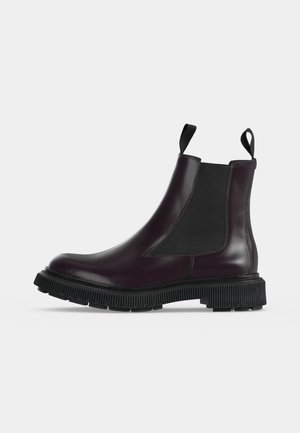 Botte Chelsea en cuir violet foncé avec panneaux latéraux élastiques noirs, languettes de traction à la cheville et semelle épaisse rainurée en caoutchouc noir.