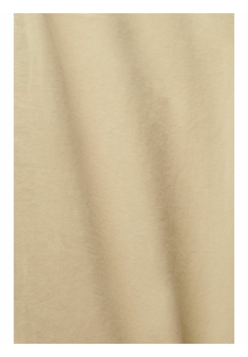 Tissu beige avec une texture lisse et un léger éclat, présentant un motif de tissage diagonal et des plis doux créant une apparence douce.