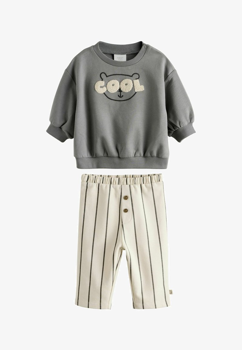 Sudadera gris con gráfico de oso y texto "COOL", combinada con pantalones cortos de rayas crema que cuentan con un cordón y dos botones.