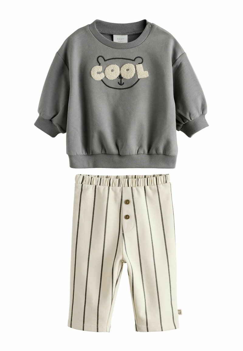 Felpa grigia con una stampa di orso e la scritta "COOL", abbinata a pantaloni corti a righe crema con vita elastica e due bottoni.