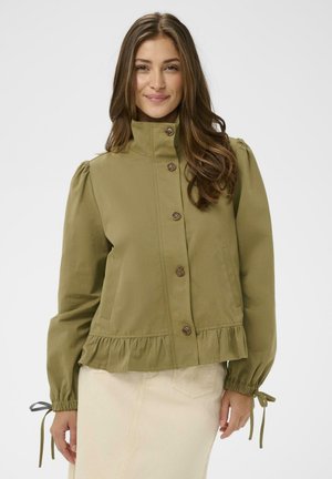 Kurtka w oliwkowej zieleni z wysokim kołnierzem, zapinana na guziki, z bufkami na rękawach i falbaną u dołu. Posiada dwie boczne kieszenie oraz sznurki przy mankietach rękawów.