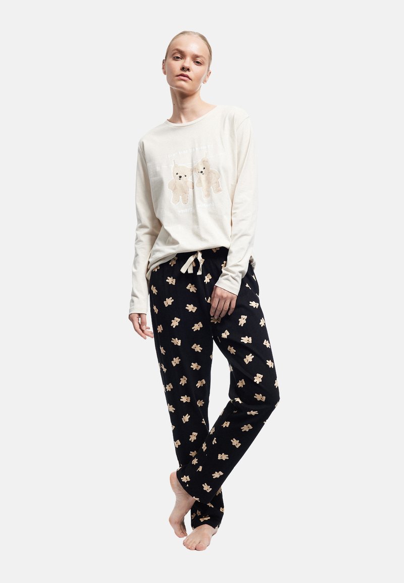 Hvid langærmet top med bjørn grafik; sorte pyjamasbukser med beige bjørn print. Løs pasform, blødt stof, elastisk talje.