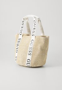 Sac en paille tissée avec des poignées en tissu blanc arborant le logo "GUESS". Forme structurée et rectangulaire dans des tons beiges avec une surface texturée.