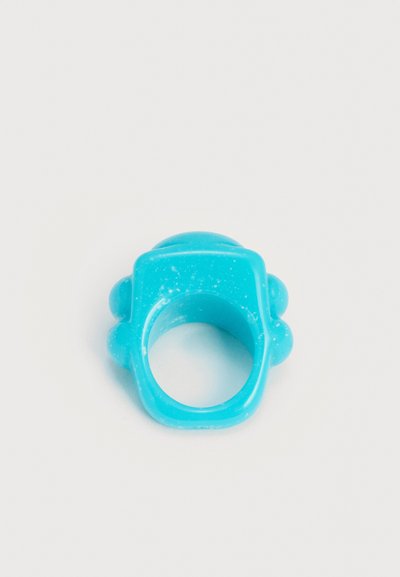 Μπλε πλαστικό δαχτυλίδι με φαρδιά τετράγωνη κορυφή και στρογγυλεμένες προεξοχές στις πλευρές, εμφανίζεται σε απλό λευκό φόντο.