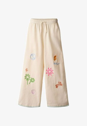 Kremowe spodnie o szerokich nogawkach z elastycznym pasem, ozdobione kolorową haftowaną roślinnością, słońcem, symbolem yin-yang i tygrysem.