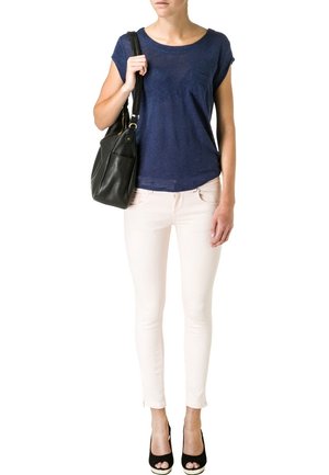 Top de manga corta azul marino, jeans ajustados rosa claro, bolso negro y tacones abiertos negros. La parte superior presenta un detalle de bolsillo.