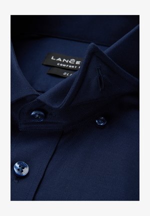 Granatowa koszula z klasycznym kołnierzem, teksturowaną tkaniną oraz dwoma ciemnoniebieskimi guzikami. Etykieta informuje: "LANCER Comfort Fit, SL."