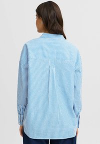 Blue and white striped shirt with a back yoke, button-down collar, and long sleeves. Features a pleat detail and cuffs at sleeve ends.
