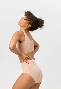 Nude-farbener Sport-BH und hochgeschnittene Unterhose aus glattem, elastischem Stoff, mit einem schlichten, nahtlosen Design und breiten Trägern.