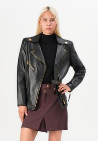 Black leather motorcycle jacket with gold zippers and buttons. Features an asymmetrical front, wide lapels, and belted waist.