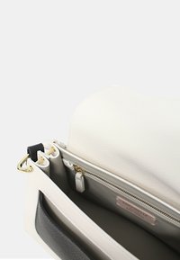 Borsa a tracolla in pelle bianca con texture liscia, dotata di accessori in oro e un accento grigio scuro. L'interno presenta una tasca con zip e diversi scomparti.