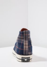 Kariert-hohe Sneaker in Marineblau und Beige, mit strukturiertem Stoff, Gummisohle und schwarzem Markenzeichen-Label an der Ferse.