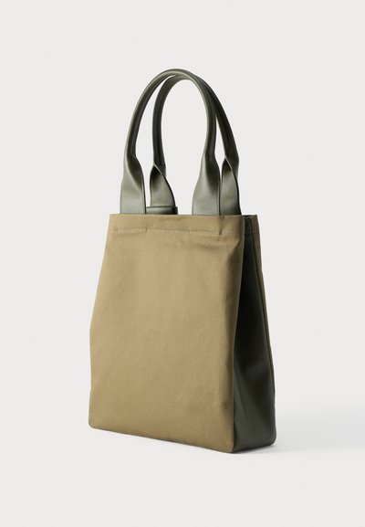 Τσάντα ώμου σε ελιά πράσινο με λαβές και πλευρές από δερματίνη με υφή, διακοσμημένη με ομαλή υφασμάτινη πρόσοψη και ορθογώνιο σχήμα που στέκεται όρθια.