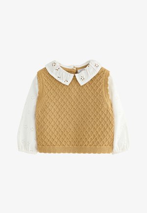 Pleteni prsluk boje gorušice s uzorkom u obliku dijamanta, nošen preko bijele bluze s izvezenim cvjetnim detaljima i okruglim ovratnikom.