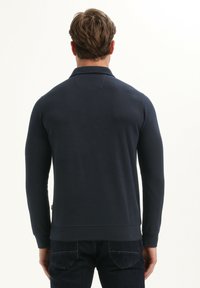 Marineblauw langemouwen polo shirt met een kraag, ribgebreide manchetten en een rechte onderrand, gemaakt van gladde stof. De achterzijde toont een eenvoudig ontwerp.