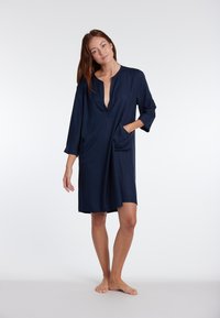 Abito blu navy, a ginocchio, con maniche a tre quarti, scollatura a V e due tasche frontali. Tessuto morbido, design casual.