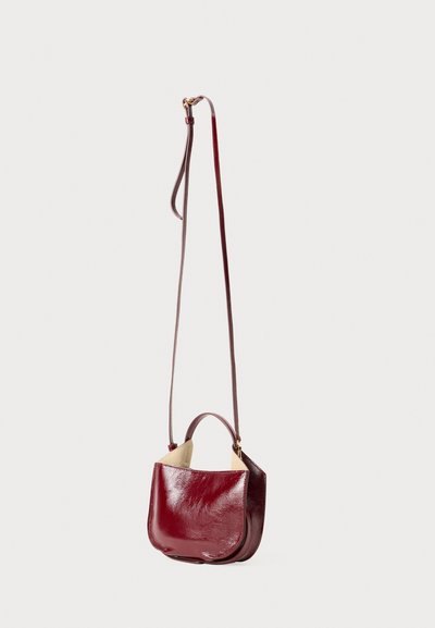 Mahogany læderhåndtaske med en blank finish, rund form, en kort håndtag og en lang rem. Har et minimalistisk design uden synligt hardware.
