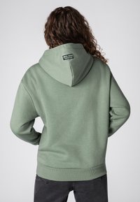 Groene hoodie met een relaxte pasvorm, verstelbare trekkoordkap, ribgebreide manchetten en zoom, en een merklabel aan de achterkant van de hals.