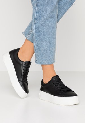 Schwarze Ledersneaker mit glatter Textur, flachen weißen Gummisohlen und passenden Schnürsenkeln. Die Schuhe haben ein Low-Top-Design und minimalistische Akzente.