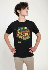 T-shirt en coton noir avec un graphique coloré d'un landspeeder et le texte "Bienvenue à Tatooine", sur fond de rayures de coucher de soleil rétro.
