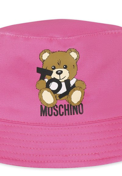 Cappello a secchiello rosa realizzato in tessuto con un orsetto dei cartoni animati che tiene un cartello con la scritta "Toy Moschino". Texture morbida con dettagli di cucitura visibili.
