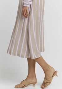 Beige csíkos szoknya világos lilás vonalakkal, lágy anyagból, térd alatt végződik, bordó slip-on sarukkal, amelyek csomós dizájnnal rendelkeznek.