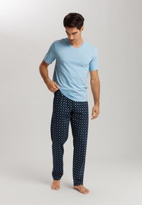 Camiseta de corte en V azul claro combinada con pantalones de pijama azul marino que presentan un patrón geométrico en azul claro. Tejido suave, ajuste relajado.