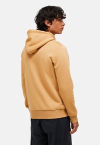 Sennepsgul hætte sweatshirt lavet af bomuldsblanding. Har en snøre i hætten og ribbede manchetter. Glat tekstur med en afslappet pasform.