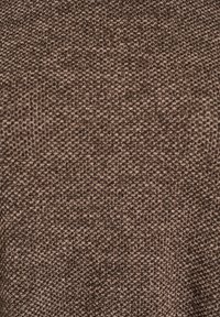Brązowa fakturowana tkanina z plecionym wzorem, z różnymi odcieniami tworzącymi subtelną głębię. Gładka i nieco elastyczna w dotyku.