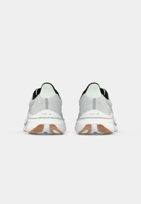 Pair of white and light grey running shoes with gum-colored outsoles, viewed from the back, on a white background.