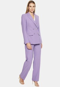 Fioletowy zestaw kostiumowy składający się z podwójnie zapinanego żakietu z srebrnymi guzikami oraz spodni prostych. Gładki materiał z dopasowanym krojem.