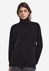 Sort turtleneck sweater lavet af blødt strikmateriale, med en ribbet krave og kant, i en afslappet pasform og lange ærmer.